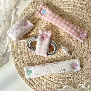 Floral fabric cable organizers with heart buttons shown on a rustic straw mat background
