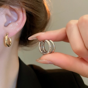 Detail view of round polished earrings in gold and silver showing mirror reflection