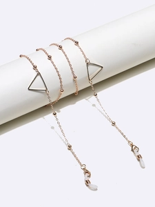 Close-up of golden glasses chain with geometric triangle charms and beaded details