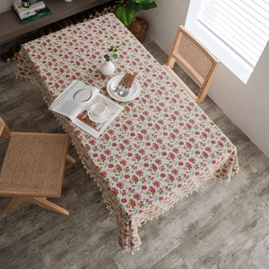 Top view of beige floral linen tablecloth with red flower patterns and tassel edges