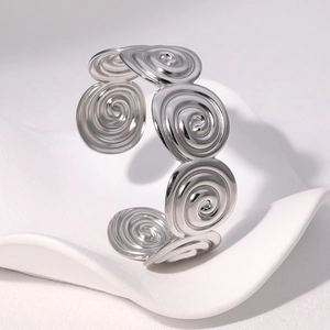 Détail d'un bracelet ouvert en acier inoxydable argenté avec des motifs de spirales