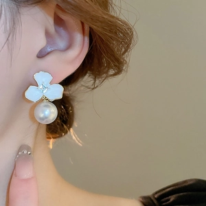 Close-up of vintage flower earrings with white enamel petals, zircon and high luster pearl