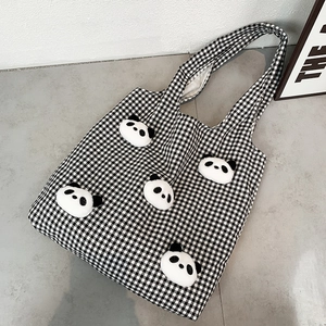 Detail of canvas tote bag with black and white checkerboard pattern and plush panda heads