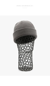 Detail der grauen Rippstrick-Beanie auf einem Display mit dicker, weicher Textur