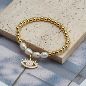 Close-up of Evil Eye pendant with freshwater pearls on a gold-beaded bracelet