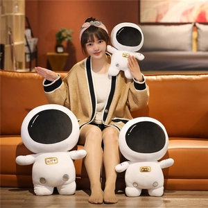 Three sizes of white plush astronaut toys shown with a model on a warm sofa