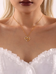 Gros plan du collier pendentif cœur doré avec lettres AMMAM et zircons étincelants