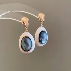 Dettaglio degli orecchini vintage in oro con perle e pietre preziose blu-nere iridescenti