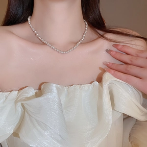 Close-up of white pearl choker necklace with rhinestone spacers worn by a model