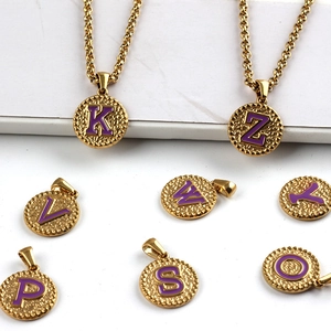 Macro shot of gold stainless steel circular pendants with purple initials and matching chains