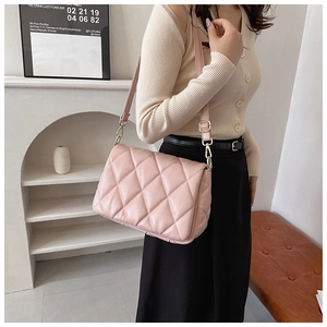 Fashionable pink quilted crossbody bag with gold hardware worn by a model in interior