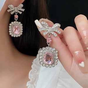 Détails de boucles d'oreilles nœud argenté avec pierres roses et strass brillants