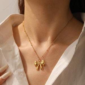 Close-up of a gold-plated bow pendant necklace on a model with a minimalist fine chain