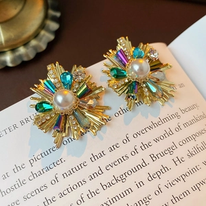 Macro shot of vintage gold earrings with pearls and colorful crystals on an open book