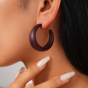 Close-up of matte dark purple acrylic C-shaped hoop earring worn on a model's ear