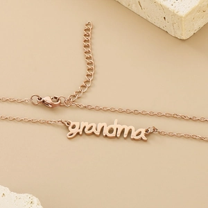 Elegant rose gold stainless steel grandma letter necklace on natural stone background