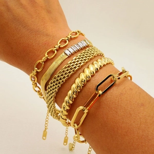 Detail shot of five stacked gold bracelets featuring snake chain and zircon inlays