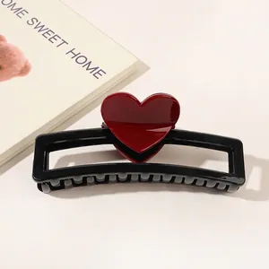 Detail of a black rectangular hair claw clip with a glossy red heart on white background