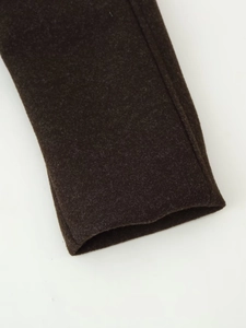 Macro detail of dark brown wool coat sleeve cuff showing stitching and thick texture