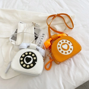 Detail of vintage telephone-style patent leather handbags in white and orange colors