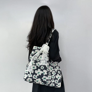 Detail of large canvas tote bag featuring floral pattern and side lace bow decoration