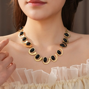 Gros plan d'un collier géométrique doré avec un pendentif en pierre noire sur un mannequin
