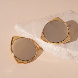 Detail showing gold-plated triangle earrings with grey inlay on natural stone base