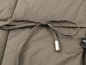 Detailed macro view of brown quilted jacket waist with adjustable drawstring and metal tips
