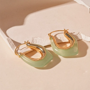 Detail of light green resin U-shaped earrings with elegant gold-plated metal edges