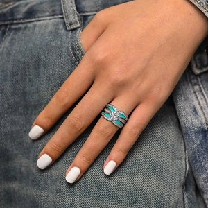 Detail of silver ring with turquoise enamel and zircon crystals on denim background