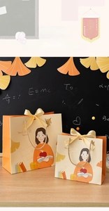 Macro shot of orange teacher gift bags with golden ribbons on a classroom blackboard background