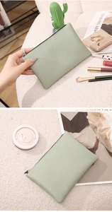 Close-up of light green lychee textured PU leather pouch with black zipper detail