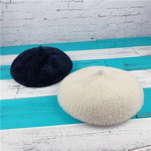 Detailed view of navy blue and off-white faux rabbit fur berets with fluffy texture