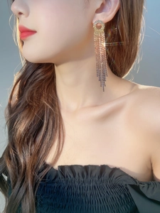 Macro detail of long gold tassel rhinestone earrings with sparkling gradient design