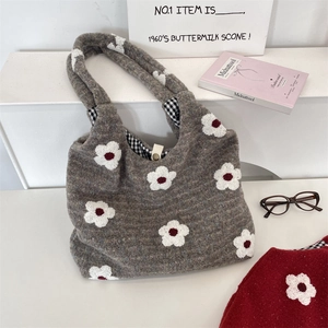 Detail of embroidered floral patterns on grey felt tote bag with checkered lining