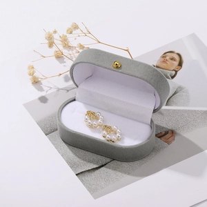 Detailed view of pearl hoop earrings with gold floral metal in a grey velvet jewelry box