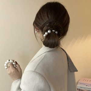Elegant large pearl hair tie shown on high bun hairstyle with minimalist warm aesthetic