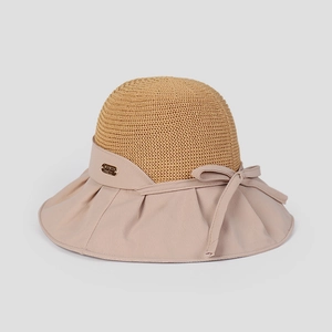 Detail of summer straw sun hat featuring a color-block brim and decorative bow with metal tag