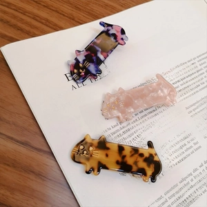 Cute cat-shaped hair clips in tortoiseshell and marble patterns on a wooden table