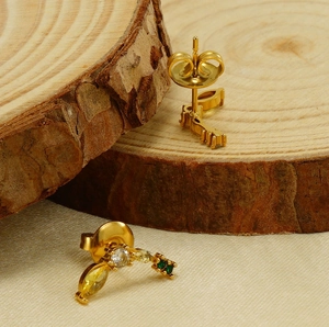 Détail de boucles d'oreilles banane plaquées or 18K avec zircons verts et jaunes