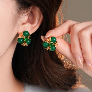 Gros plan de boucles d'oreilles vintage à fleurs avec perles vertes et design doré