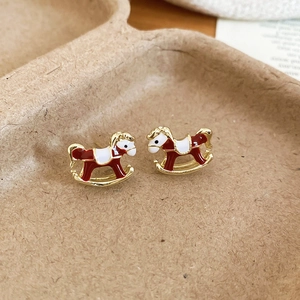 Gros plan de boucles d'oreilles cheval à bascule avec émail rouge et blanc sur cadre doré