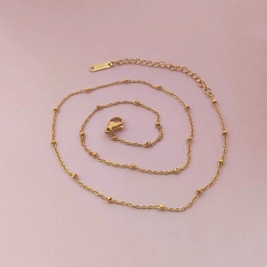 Close-up of gold stainless steel beaded chain necklace with lobster clasp and adjustable link