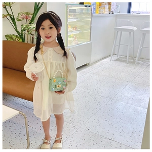 Close-up of a girl wearing a mint green mini pearl handbag with a beige dress in a cafe