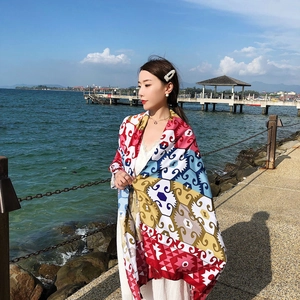 Detail of bohemian red silk scarf showing geometric patterns in sunny beach setting