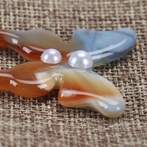 Macro shot of acetic acid butterfly hair pin with pearls on woven linen texture