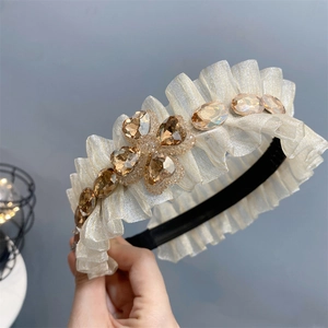 Detailed view of beige pleated headband with sparkling champagne crystal flowers