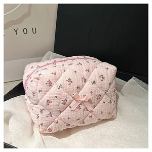 Close-up of pink floral quilted cosmetic bag with ribbon bow and zipper detail