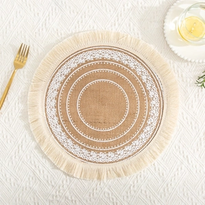 Close-up of a jute placemat with white circular patterns and beige tassels on table