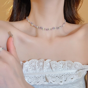 Close-up of a floral beaded necklace with purple, white, and yellow beads on a female model